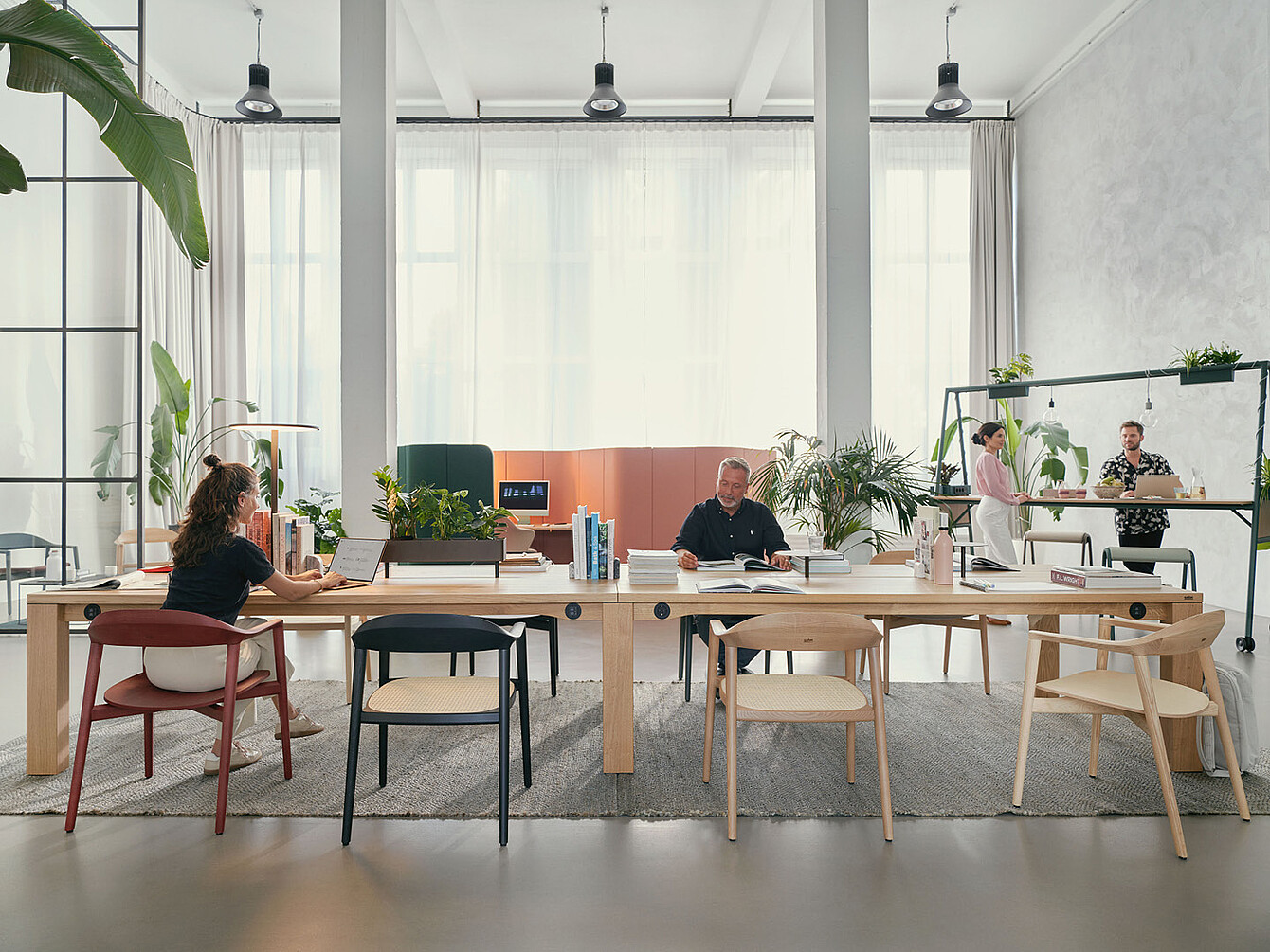 Moderne kantoorruimte met grote se:café-teamtafel, vier mensen aan het werk en planten op en rond de tafel