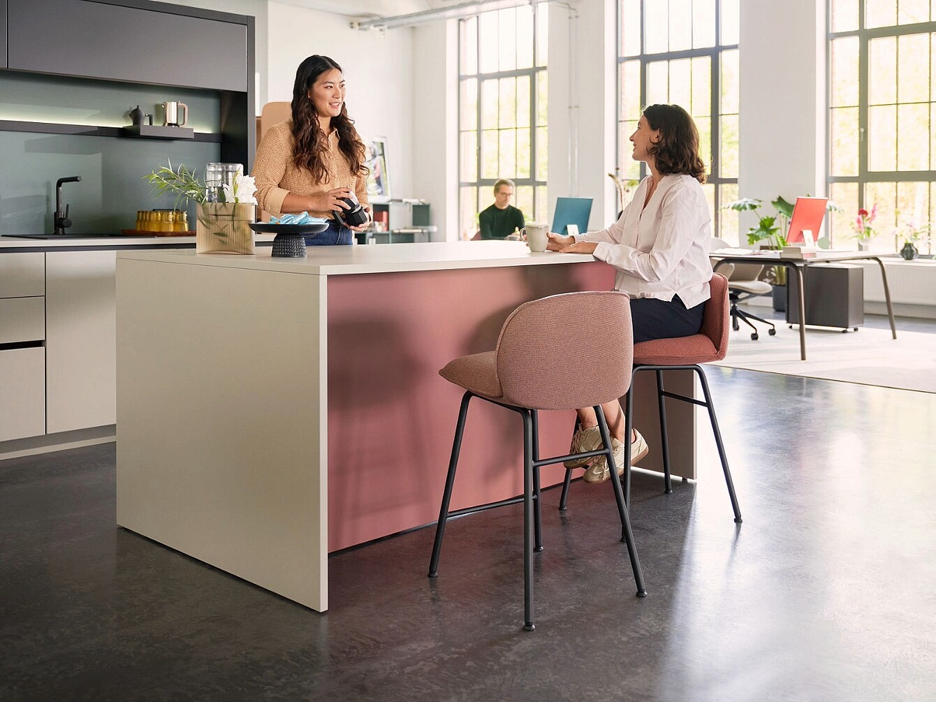 Deux femmes dans un café-bar, l’une debout derrière le comptoir et l’autre assise sur un tabouret haut, une tasse à la main