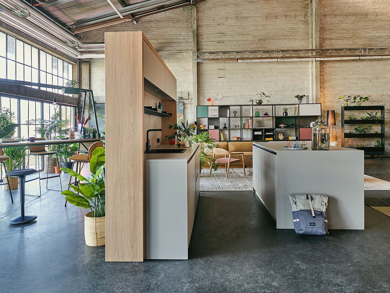 Intérieur moderne du se:café bar : un îlot central, des étagères ouvertes agrémentées de plantes et de décorations, ainsi que de grandes baies vitrées de style industriel