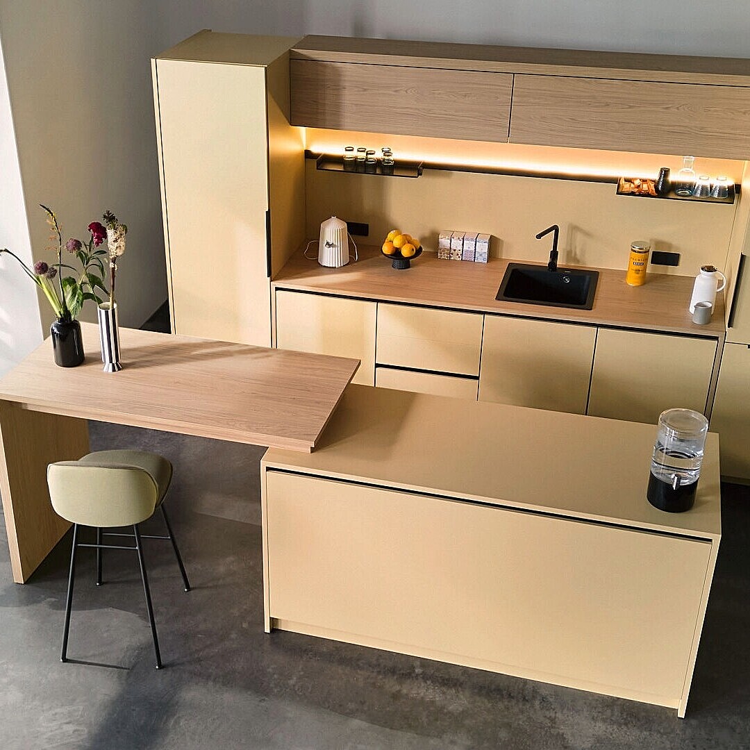Modern café bar setup with tall cabinets, a wooden countertop, integrated sink, and a single chair at the bar extension