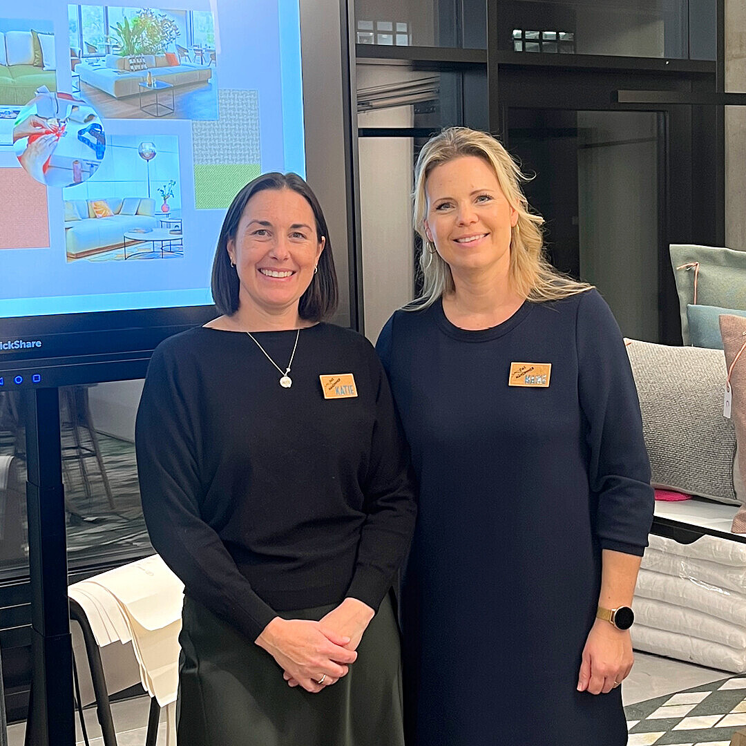 Zwei Frauen mit Namensschildern stehen vor einem Bildschirm mit Präsentationsfolien zum Event "Soft Seating & Design to go" von Sedus und Gabriel im IDX 81 in München.