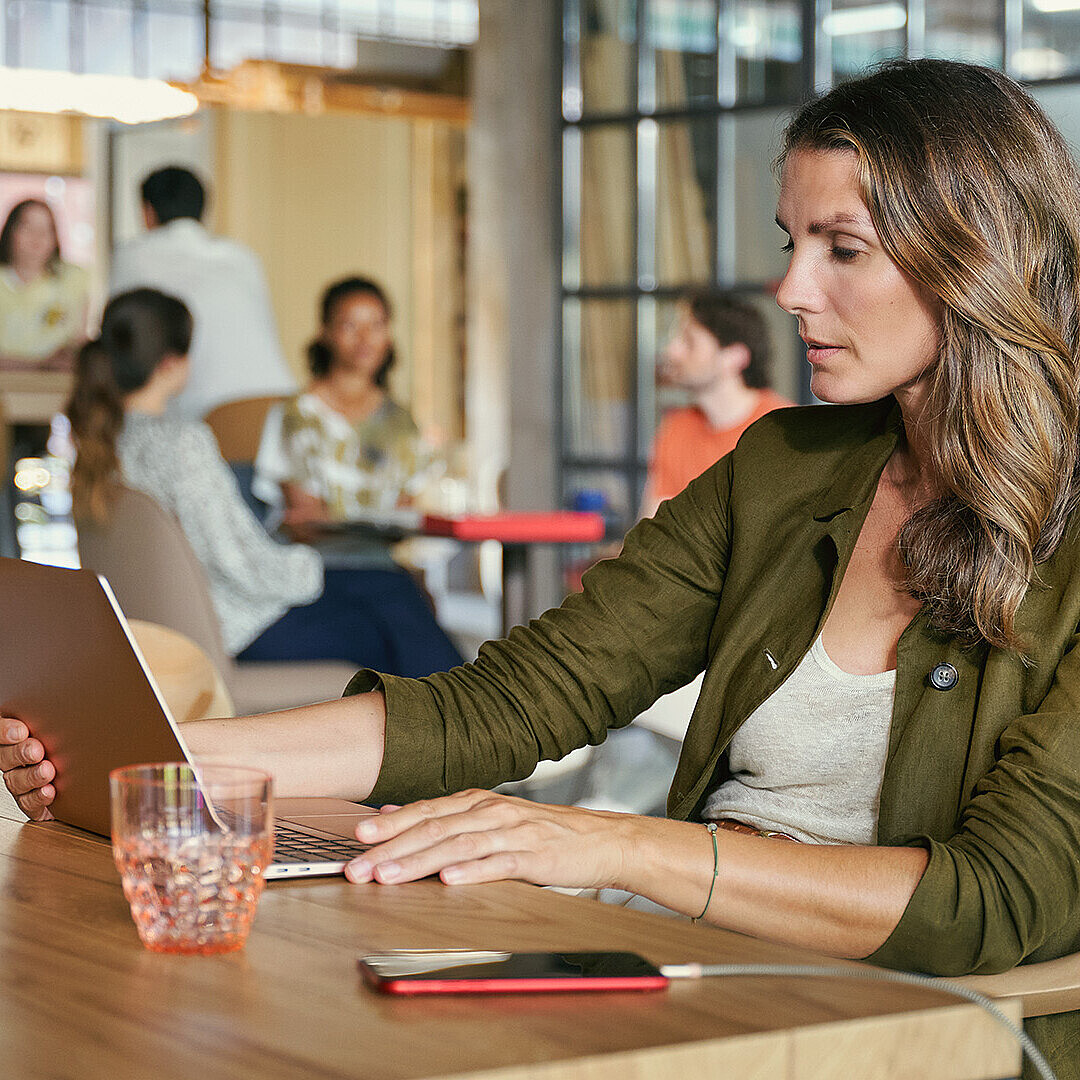 Woman in olive blazer working on tablet at Smart Café, a flexible office space blending work, networking, and relaxation
