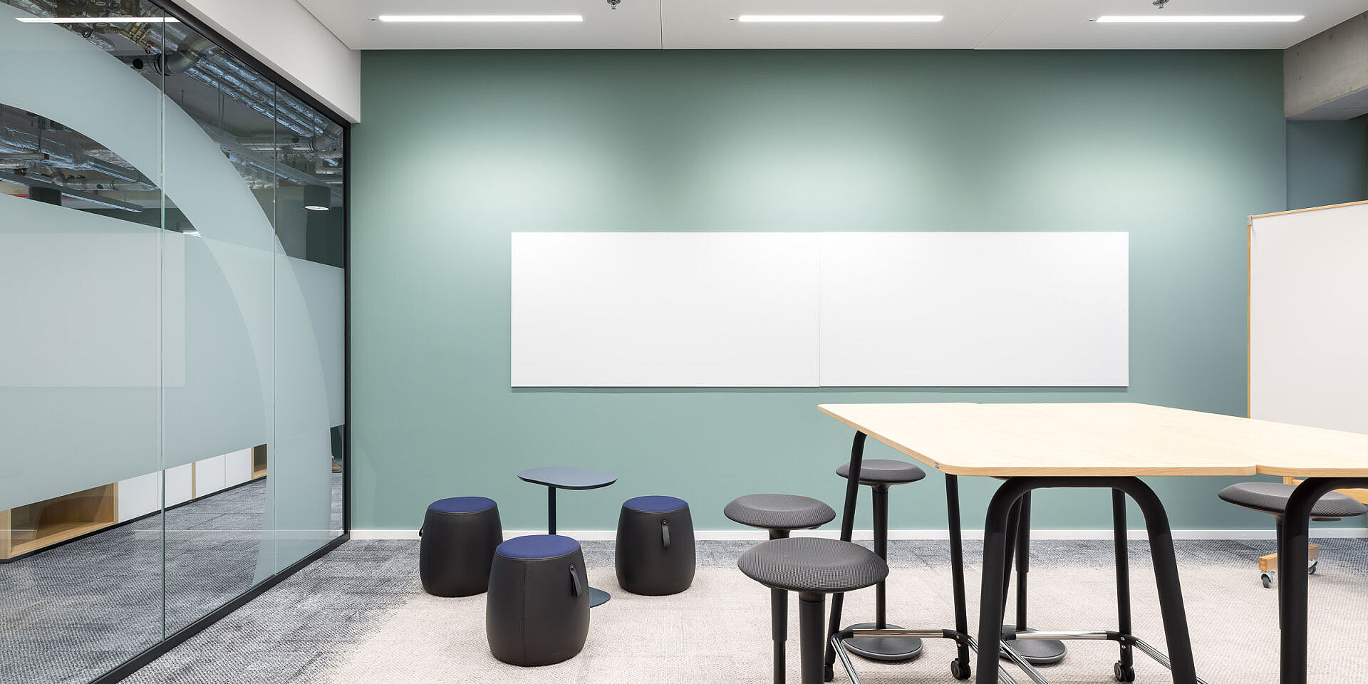 Moderna sala de reuniones con mesa de taller se:lab high desk, asientos de pie se:fit y taburetes universales se:dot para un trabajo ágil y la colaboración. 