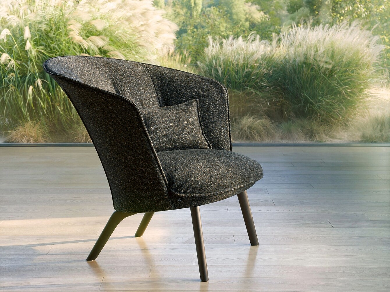 Moderne, zachte fauteuil met gebogen rugleuning en klein kussen op een houten vloer voor een raam met planten buiten