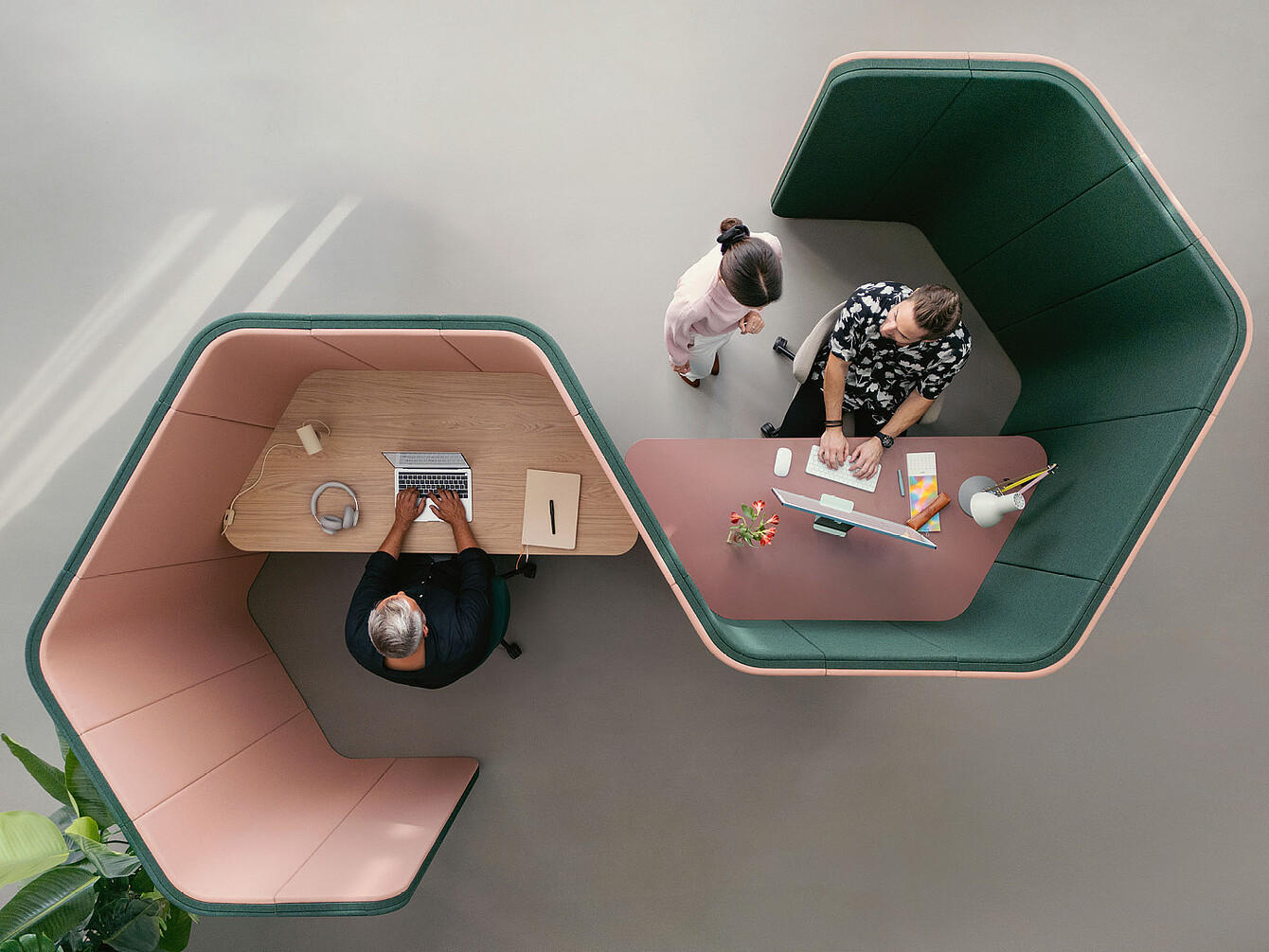 Twee mensen werken in aangrenzende hexagonale se:hive-kantoorpods, de ene met een laptop en de andere met een desktopcomputer, gezien van bovenaf