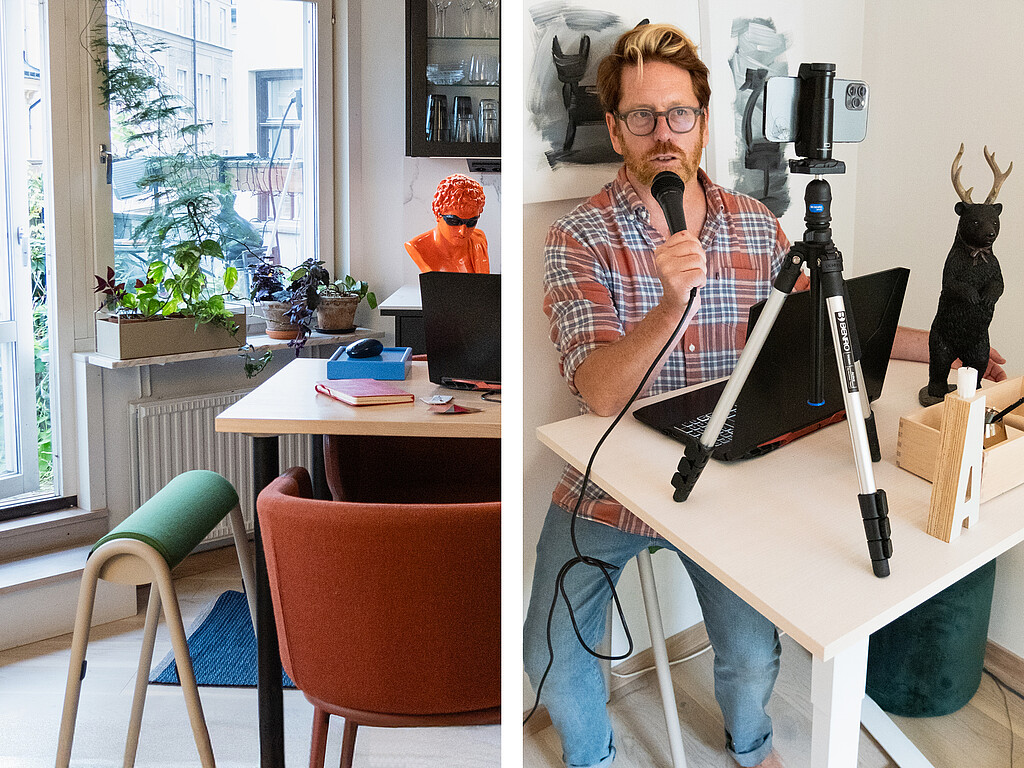 Person sitzt an einem weißen Tisch mit Laptop und Mikrofon vor einem Smartphone auf einem Stativ, im Hintergrund Kunstwerke und Pflanzen
