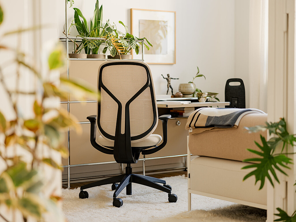Ergonomischer Bürostuhl mit Netzrückenlehne in einem hellen Homeoffice mit Pflanzen und Schreibtisch