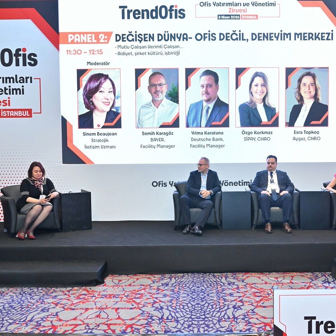 Panel of six people seated on stage in front of a large screen displaying the TrendOfis Summit event title and panelist names and photos