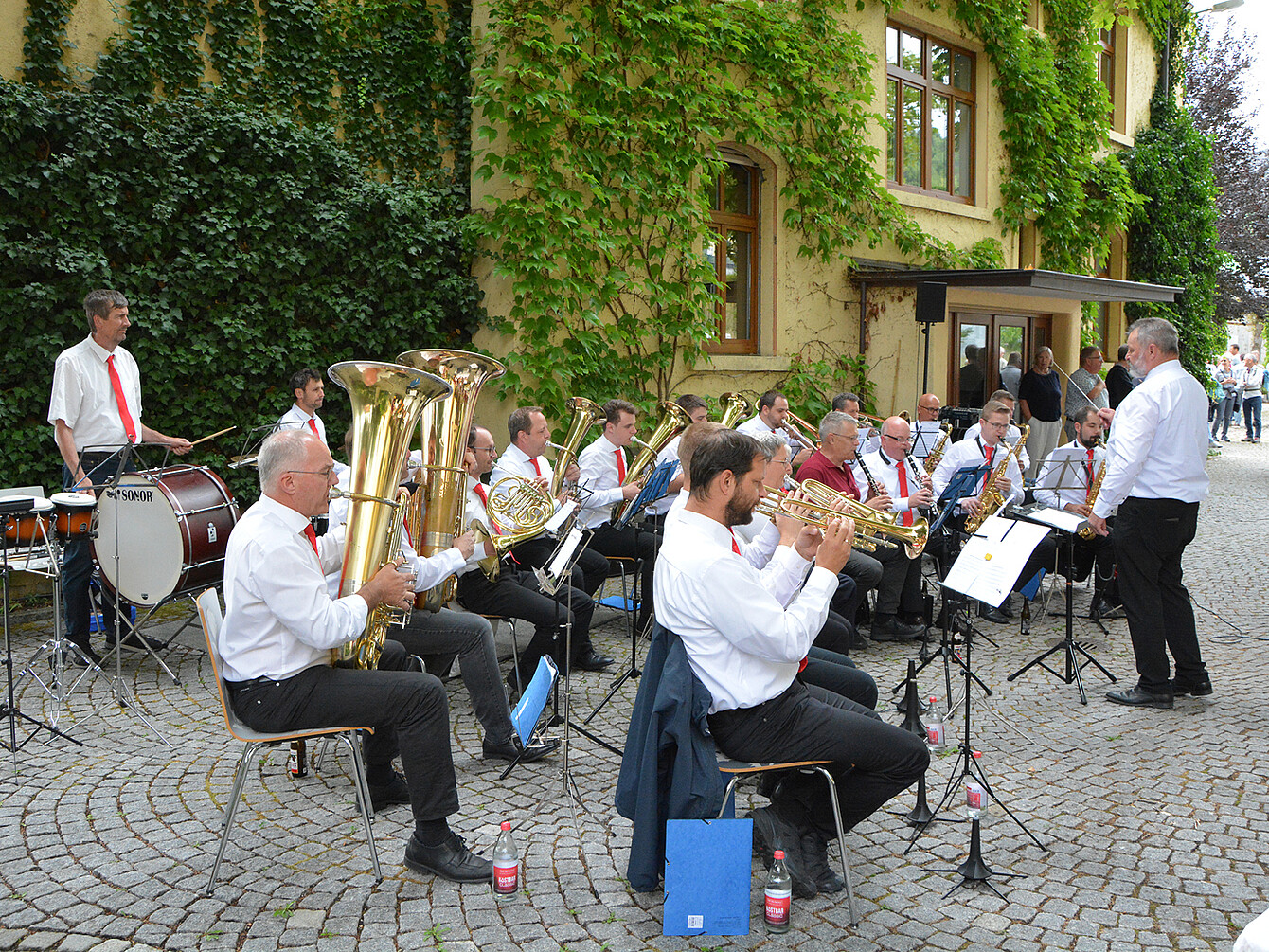 Werkskapelle der Firma Aebi Schmidt aus St. Blasien spielt unter Leitung von Stefan Köpfer bei Sedus Werksmusik Jubiläumskonzert im Freien vor Gebäude mit Efeu