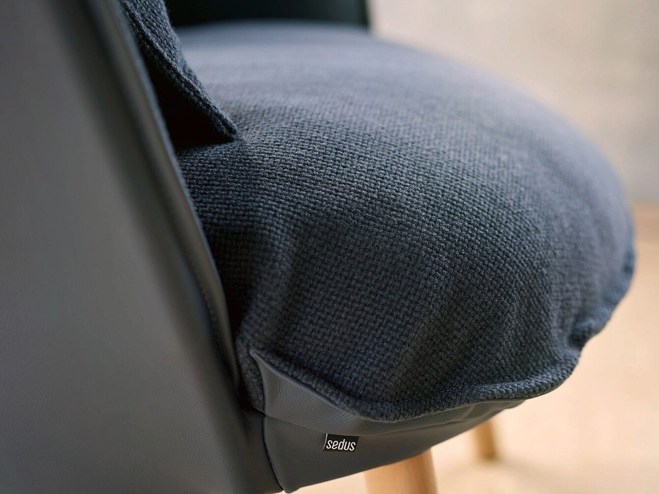 Close-up van een stoelzitting van se:cove met gestructureerde bekleding en een klein stoflabel met het Sedus-merk