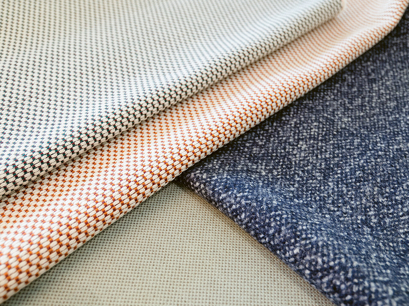 Close-up van verschillende stofstalen met verschillende texturen en patronen, die het belang van materiaalkeuze bij het ontwerpen benadrukken.