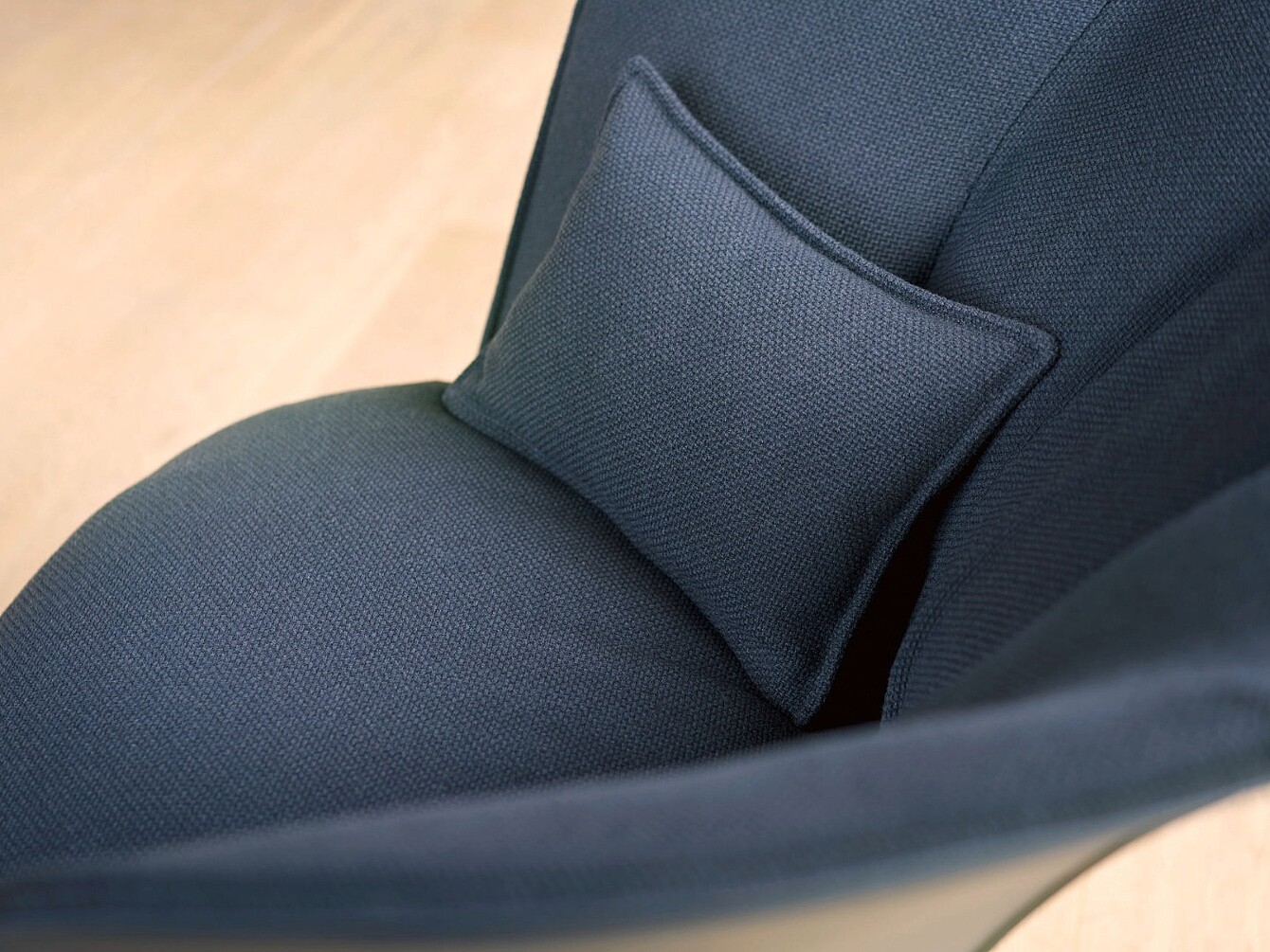 Nahaufnahme eines dunkelblauen Sessels mit kleinem rechteckigem Kissen