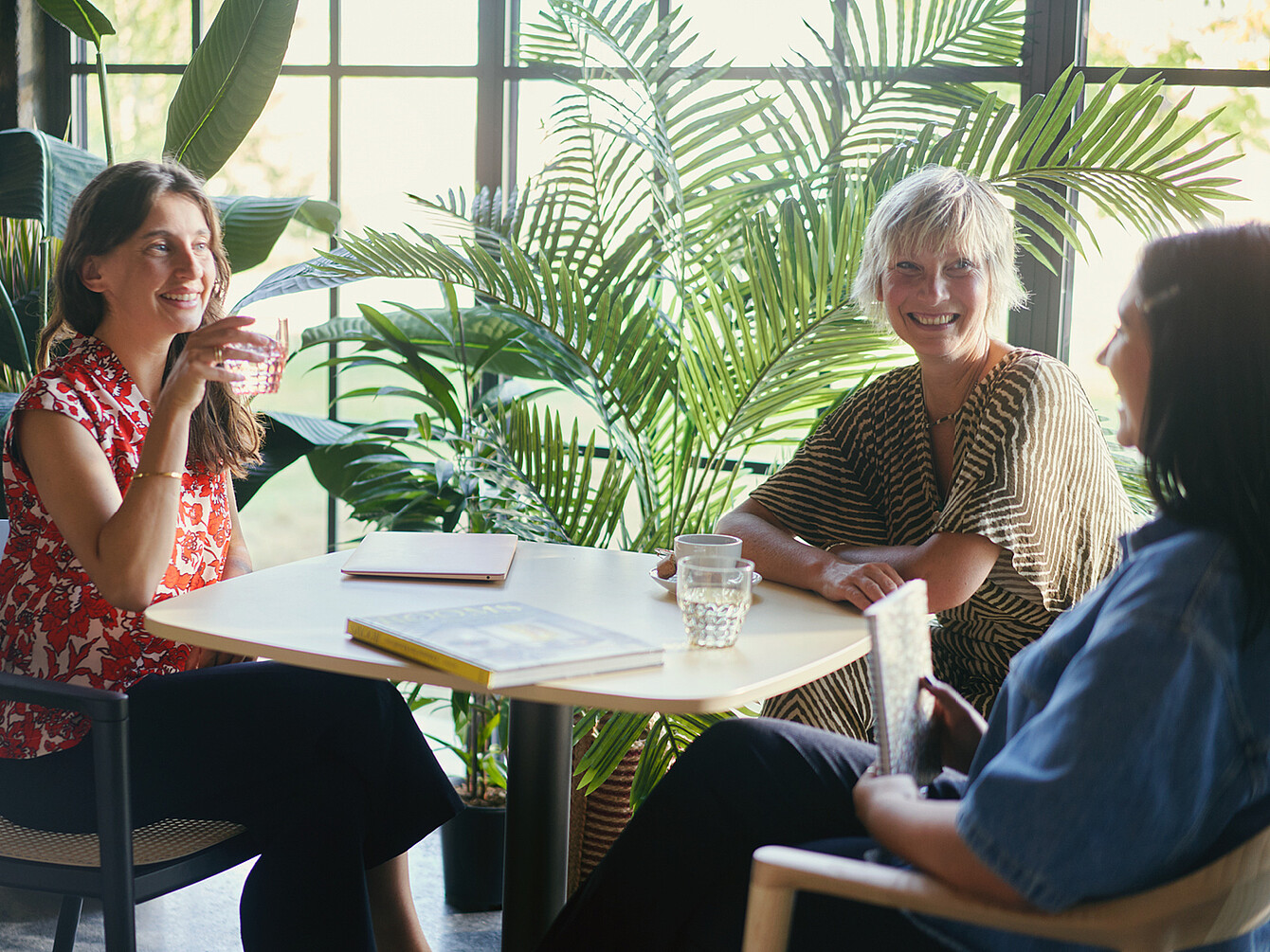 Drie vrouwen voeren een levendig gesprek op kantoor